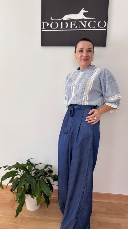 Detalle de una mujer llevando el Pantalón Adara azul de corte palazzo, con cinturilla alta anudada y pinzas, estilizando la figura con caída fluida.